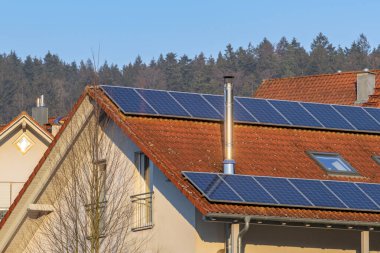 Çatıda güneş panelleri ve paslanmaz çelik bacası olan ayrı bir ev.