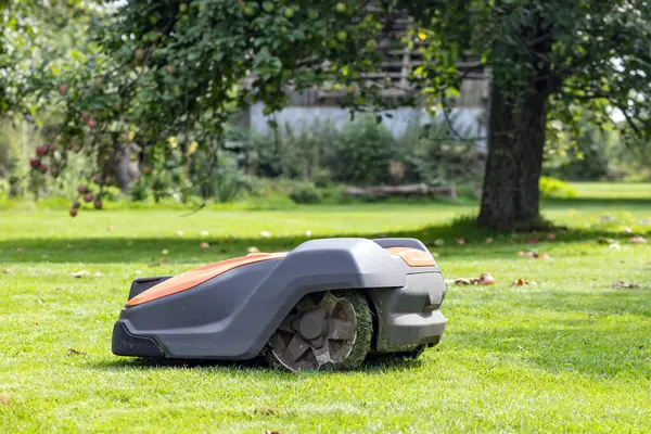 stock image Robotic lawnmower in the garden with apple tree