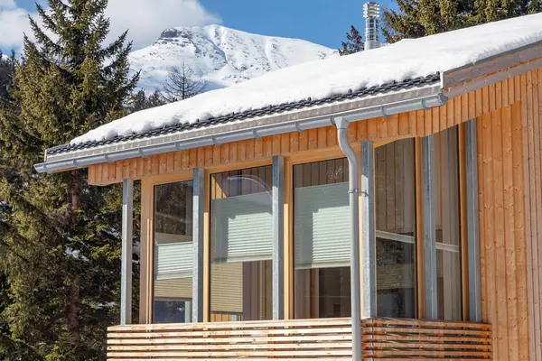 Alplerde büyük pencereli ahşap bir ev.