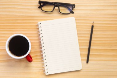 Bilgisayarlı ahşap masa ofisi, akıllı telefon ve bir fincan kahveyle birlikte diğer iş malzemeleri. Metni kopyalamak için üst görünümü kullan. Desenci çalışma alanı düz masa üzerinde temel elementler yatıyordu.