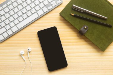 Bilgisayarlı ahşap masa ofisi, akıllı telefon ve bir fincan kahveyle birlikte diğer iş malzemeleri. Metni kopyalamak için üst görünümü kullan. Desenci çalışma alanı düz masa üzerinde temel elementler yatıyordu.