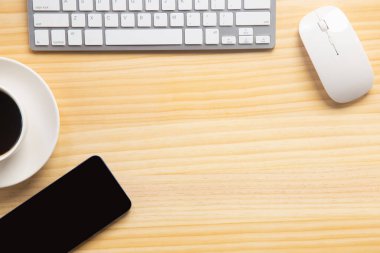Bilgisayarlı ahşap masa ofisi, akıllı telefon ve bir fincan kahveyle birlikte diğer iş malzemeleri. Metni kopyalamak için üst görünümü kullan. Desenci çalışma alanı düz masa üzerinde temel elementler yatıyordu.