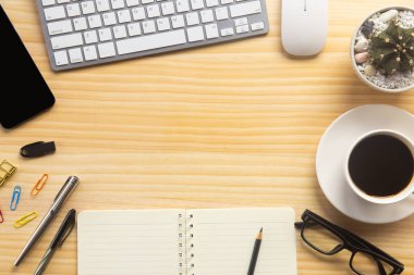 Bilgisayarlı ahşap masa ofisi, akıllı telefon ve bir fincan kahveyle birlikte diğer iş malzemeleri. Metni kopyalamak için üst görünümü kullan. Desenci çalışma alanı düz masa üzerinde temel elementler yatıyordu.