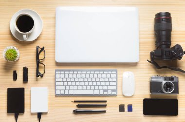 Bilgisayarlı ahşap masa ofisi, akıllı telefon ve bir fincan kahveyle birlikte diğer iş malzemeleri. Metni kopyalamak için üst görünümü kullan. Desenci çalışma alanı düz masa üzerinde temel elementler yatıyordu.