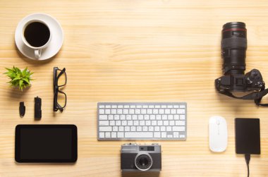 Bilgisayarlı ahşap masa ofisi, akıllı telefon ve bir fincan kahveyle birlikte diğer iş malzemeleri. Metni kopyalamak için üst görünümü kullan. Desenci çalışma alanı düz masa üzerinde temel elementler yatıyordu.