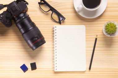 Bilgisayarlı ahşap masa ofisi, akıllı telefon ve bir fincan kahveyle birlikte diğer iş malzemeleri. Metni kopyalamak için üst görünümü kullan. Desenci çalışma alanı düz masa üzerinde temel elementler yatıyordu.