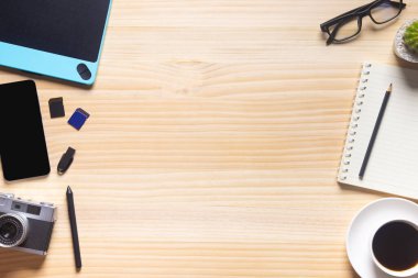 Bilgisayarlı ahşap masa ofisi, akıllı telefon ve bir fincan kahveyle birlikte diğer iş malzemeleri. Metni kopyalamak için üst görünümü kullan. Desenci çalışma alanı düz masa üzerinde temel elementler yatıyordu.