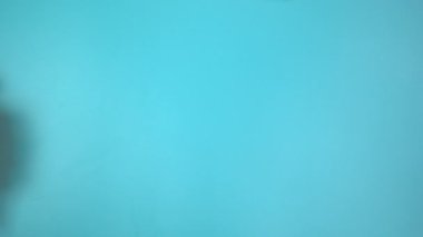 Görüntü 4K. Mavi arka planda pembe kurdele tutan eller. Göğüs kanseri farkındalığı, erkek göğüs kanseri hastalığı, Dünya Kanser Günü. Sağlık hizmetleri ya da hastane ve sigorta kavramı.