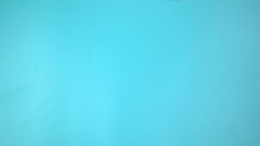 Görüntü 4K. Mavi arka planda pembe kurdele tutan eller. Göğüs kanseri farkındalığı, erkek göğüs kanseri hastalığı, Dünya Kanser Günü. Sağlık hizmetleri ya da hastane ve sigorta kavramı.