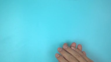 Görüntü 4K. Mavi arka planda pembe kurdele tutan eller. Göğüs kanseri farkındalığı, erkek göğüs kanseri hastalığı, Dünya Kanser Günü. Sağlık hizmetleri ya da hastane ve sigorta kavramı.