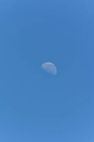 The waning moon in a blue sky. Nature.