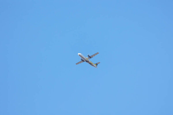 A twin-engine plane flying in a blue sky between clouds. Transportation.