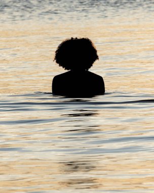 Gün batımında gölün sularının keyfini çıkaran bir kadının silueti. Yaşam biçimi.