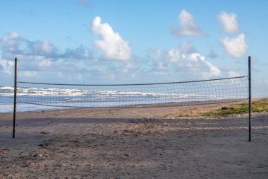 Mavi gökyüzünün altındaki kumlu bir sahilde voleybol oynamak için bir ağ.