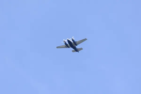 Silhouette of a twin-engine plane flying in a blue sky between clouds. Transportation. Aircraft.