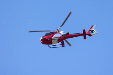Kırmızı bir helikopter mavi gökyüzünü geçiyor. Şehir ulaşımı. Trip. Macera.