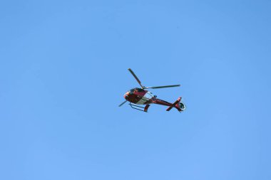 Kırmızı bir helikopter mavi gökyüzünü geçiyor. Şehir ulaşımı. Trip. Macera.