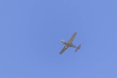 A Small silver plane. A single engine plane crosses the blue sky. Transportation.