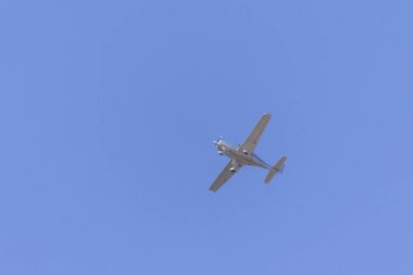 A Small silver plane. A single engine plane crosses the blue sky. Transportation.