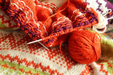 Örgü iğneleri ve iplik yumağıyla örülmüş bir örgü parçası.