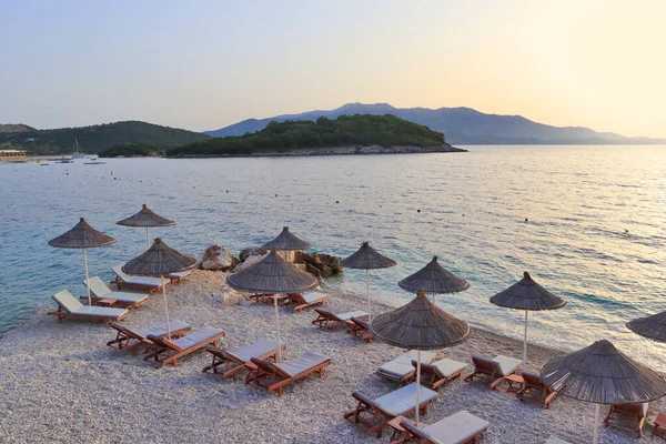 Beach with sun beds and umbrellas at sunset in Ksamil, Albania