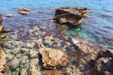 Kıbrıs Rum Kesimi 'nde deniz kenarındaki berrak mavi su ve taşların üst görüntüsü