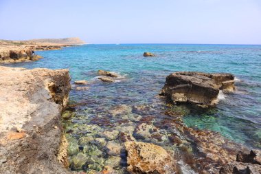 Kıbrıs Rum Kesimi 'nde deniz kenarındaki berrak mavi su ve taşların üst görüntüsü