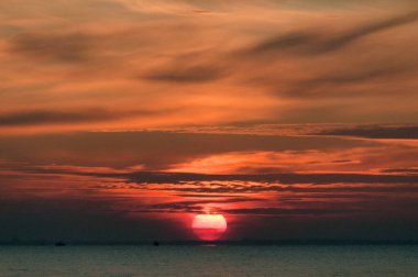 Kırmızı bir atmosferde gün batımının deniz manzarası