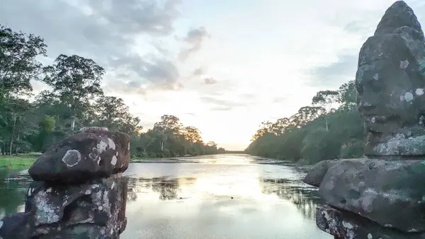 Kayalık bir kıyı şeridi ve arkasında bulutlu bir gökyüzü olan güzel bir göl.