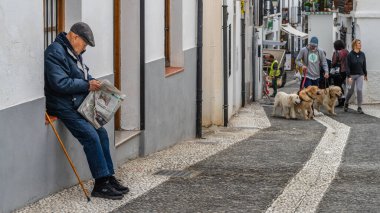 Granada, İspanya, 14 Şubat 2024. Granada 'daki Albaisin mahallesinde popüler bir sokakta gazete okuyan bir beyefendi. Yüksek kalite fotoğraf