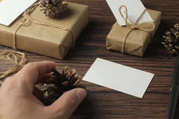 男性の手は新しい年の贈り物や書き込みカードを包む茶色の木製のテーブルに — ストック写真