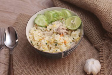 Pork Fried Rice, Çin usulü kızarmış pilav, salatalıklı ve limonlu, kahverengi ahşap bir masada servis edilmiş..