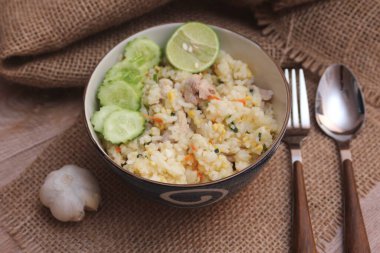 Pork Fried Rice, Çin usulü kızarmış pilav, salatalıklı ve limonlu, kahverengi ahşap bir masada servis edilmiş..
