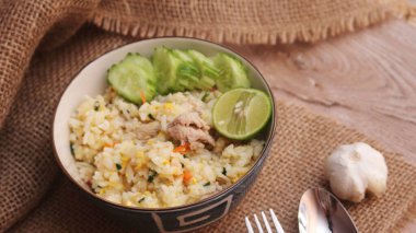 Pork Fried Rice, Çin usulü kızarmış pilav, salatalıklı ve limonlu, kahverengi ahşap bir masada servis edilmiş..