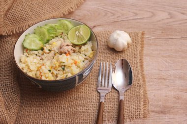 Pork Fried Rice, Çin usulü kızarmış pilav, salatalıklı ve limonlu, kahverengi ahşap bir masada servis edilmiş..