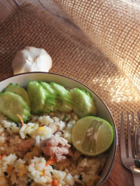 Pork Fried Rice, Çin usulü kızarmış pilav, salatalıklı ve limonlu, kahverengi ahşap bir masada servis edilmiş..