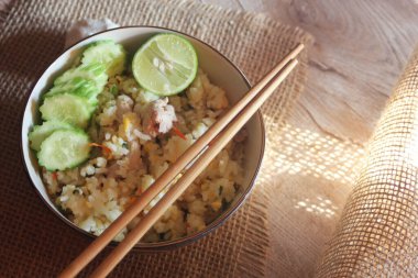 Pork Fried Rice, Çin usulü kızarmış pilav, salatalıklı ve limonlu, kahverengi ahşap bir masada servis edilmiş..