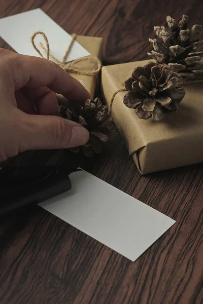 リサイクルされた紙やギフトカード 新年のギフトボックスに包まれたギフトボックス木製のテーブル コピースペース 茶色のクリスマスギフトボックスに置かれます — ストック写真