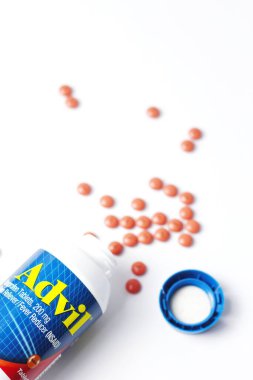 Washington, ABD - 02 Ekim 2022: Advil şişeleri ve haplar beyaz bir masaya yayıldı. Ateş, ağrı kesici, popüler Amerikan ağrı kesici, ibuprofen..