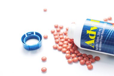 Washington, ABD - 02 Ekim 2022: Advil şişeleri ve haplar beyaz bir masaya yayıldı. Ateş, ağrı kesici, popüler Amerikan ağrı kesici, ibuprofen..