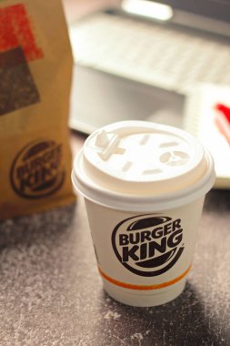 Bangkok, Thailand - January 18 2023 : Burger King's coffee cup and laptop on table in restaurant. Fast food business background