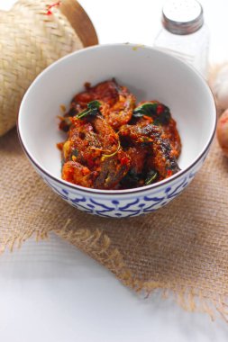 Baharatlı Kızarmış Yayın Balığı Tayland usulü beyaz bir masada servis edilir..