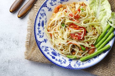 Somtum, Tayland baharatlı papaya salatası beyaz arka planda, uluslararası Tayland yemeği bilinen ve popüler, papaya ve domatesle yapılan, ekşi, tatlı ve baharatlı.