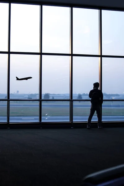 Silhouette of a man standing in front of the window at the airport