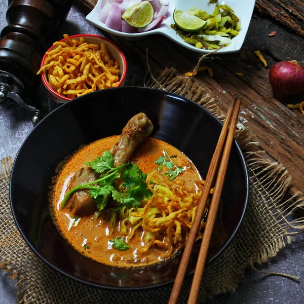 Kuzey Tayland Körili Erişte Tavuklu, Kuzey Tayland Gıda Yüksek Kontrastlı fotoğraf, yemek fotoğrafçılığı, dokulu ahşap masa.