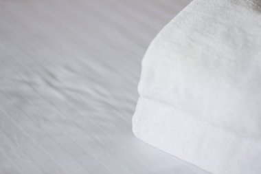 Otel yatağında beyaz temiz havlulara odaklan. Oda servisi konsepti. Yeni yatak takımları ve kişisel hijyen ürünleri üzerine yakın plan beyaz..