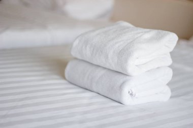 Oteldeki yatakta beyaz havlu yığını.