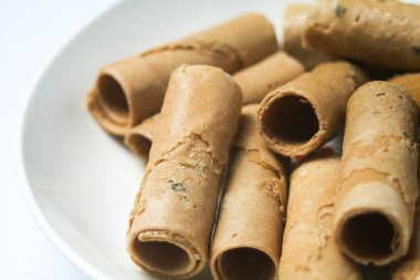 Beyaz arka planda beyaz bir tabağa yerleştirilmiş çıtır yumurta rulosu ya da kıtır altın kıvırcık. İzole edilmiş.