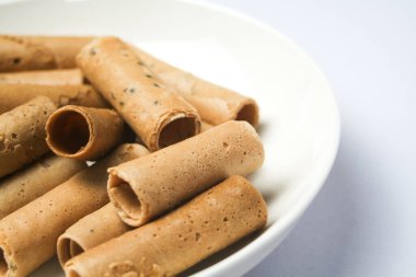 Beyaz arka planda beyaz bir tabağa yerleştirilmiş çıtır yumurta rulosu ya da kıtır altın kıvırcık. İzole edilmiş.