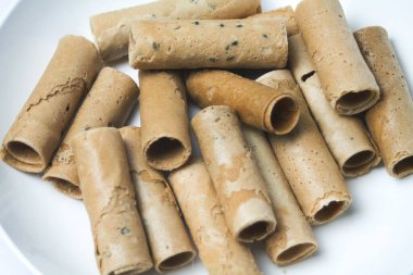 Beyaz arka planda beyaz bir tabağa yerleştirilmiş çıtır yumurta rulosu ya da kıtır altın kıvırcık. İzole edilmiş.